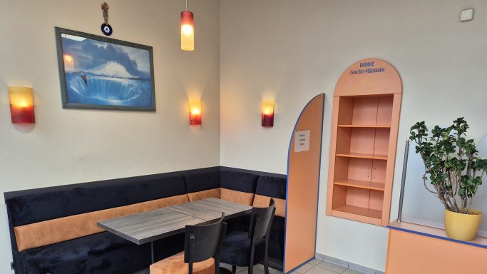 Gemütliche Ecke im Euro Döner Bad Kissingen mit Tisch, Stühlen, Pflanzen und bunten Wandleuchten.