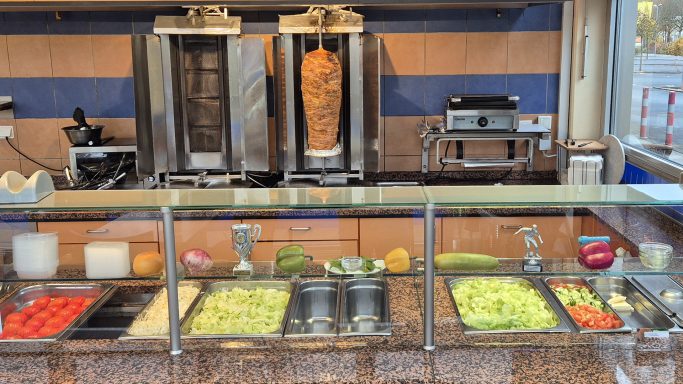Euro Döner Bad Kissingen mit Gyrosstand und Gemüsebar mit frischen Zutaten wie Tomaten, Salat und Zwiebeln.